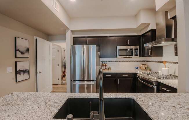 A modern kitchen with a black sink and granite countertop.