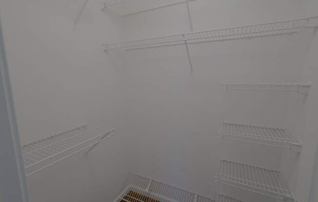 a walk in closet with white walls and shelves
