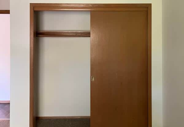 A brown door is in a white room.