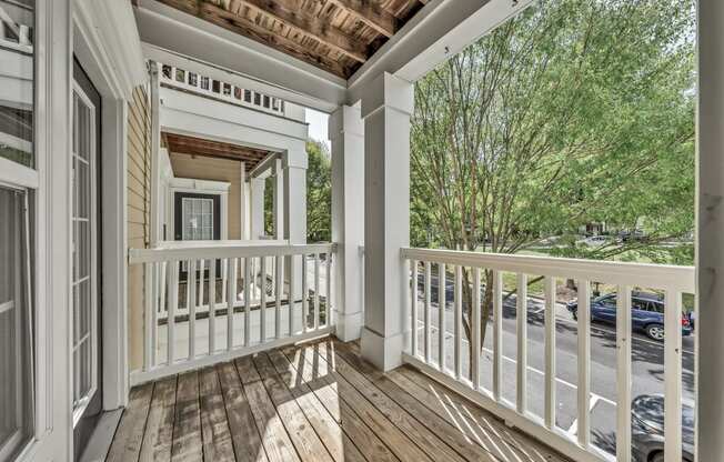 a covered porch with wood floors and white railings