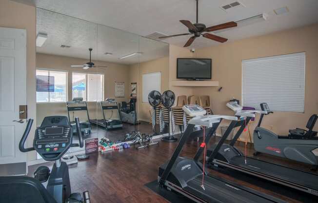 the gym has plenty of exercise equipment and a tv