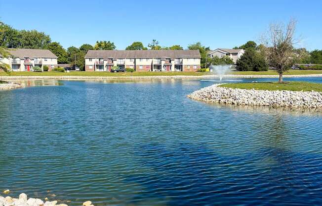 A serene lake surrounded by a grassy area and a stone wall.