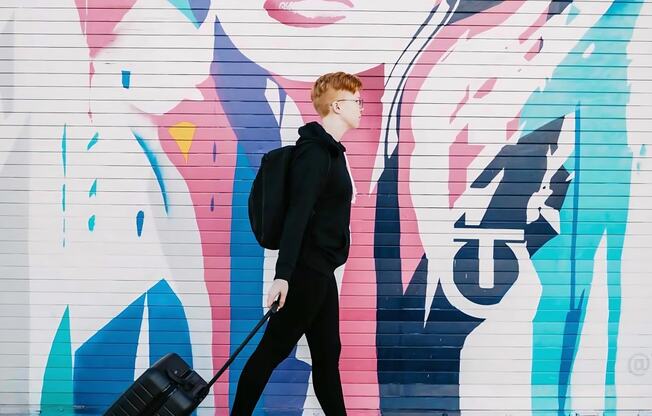 Person Walking in Front of Colorful Mural