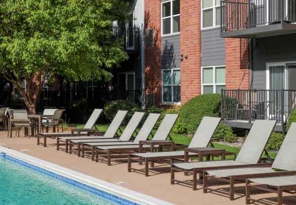 A pool with chairs and a building in the background.