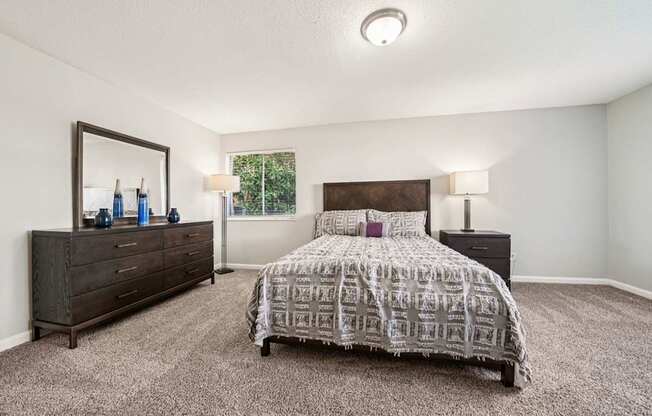 A bedroom with a bed, dresser, and mirror.
