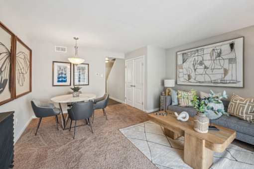 A living room with a grey couch, a white table, and a painting on the wall at Staples Mill Townhomes Apartments, Richmond, Virginia