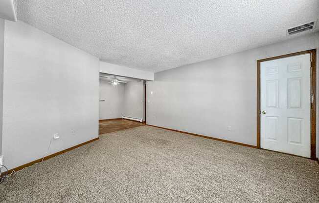 A room with a carpeted floor and a door on the right side.