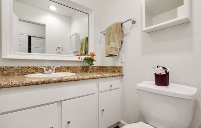 Bathroom with single vanity, granite countertops, white cabinets