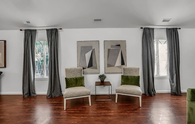 a living room with two chairs and two paintings on the wall