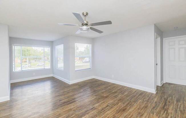 A room with a ceiling fan and wooden flooring.