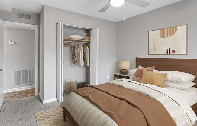 A bedroom with a large bed and a closet with clothes hanging.