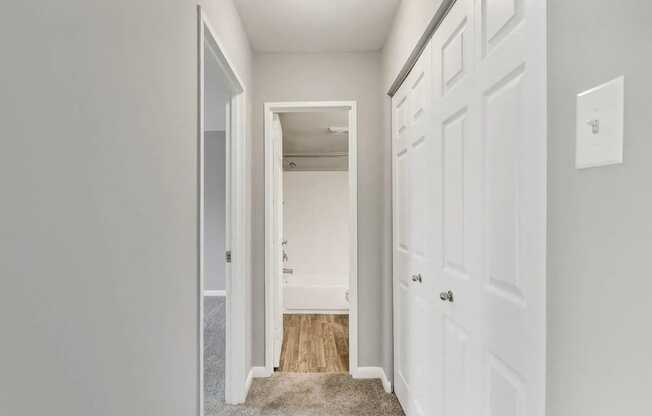 A hallway with a white door and a white wall.