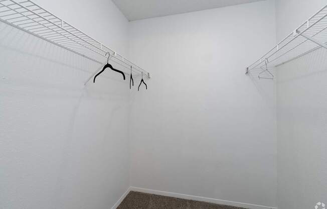 Empty white closet with clothes hangers.