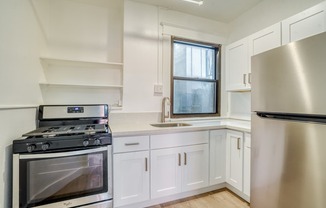 A kitchen with a stove, sink, and refrigerator.
