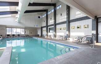 A large indoor swimming pool with lounge chairs and a glass wall.