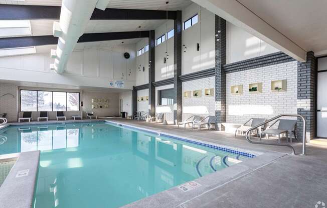 A large indoor swimming pool with lounge chairs and a glass wall.
