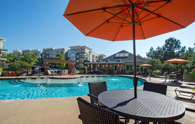 A patio with a table and chairs under an orange umbrella.