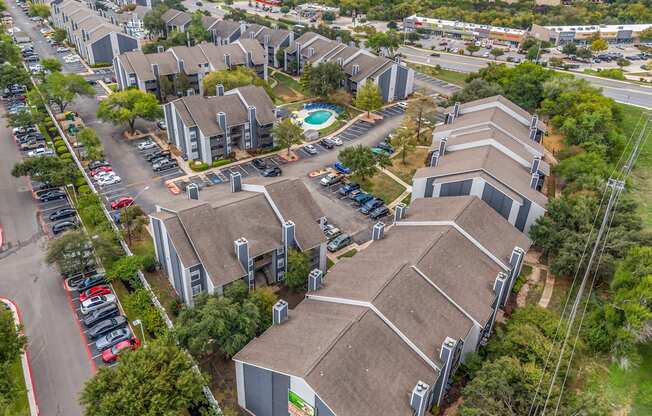 an aerial view of several buildings with cars parked in a parking lot