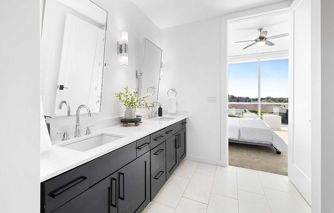 A bathroom with a black vanity and a white ceiling fan.
