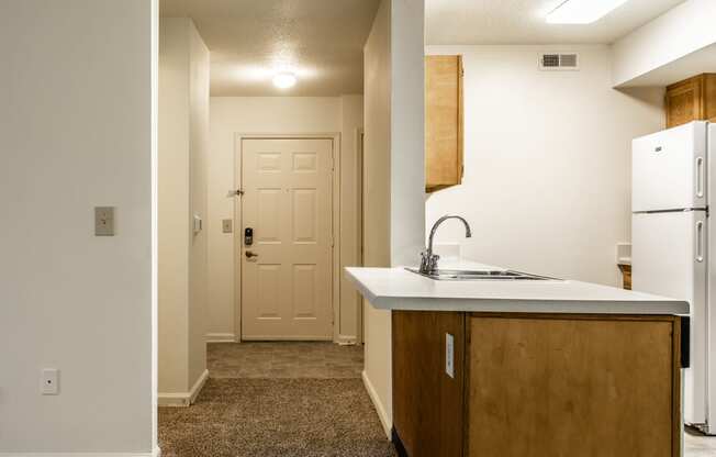 an empty kitchen with a sink and refrigerator and a door at Pheasant Run in Lafayette, IN 47909