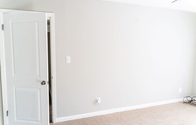 A white door is open to a room with a carpeted floor.