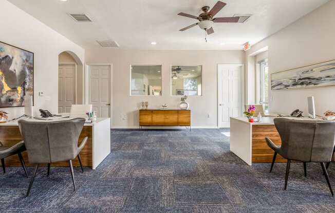 a living room with chairs and a desk and a ceiling fan