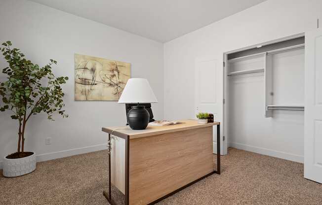 a room with a desk with a lamp and a door to a closet