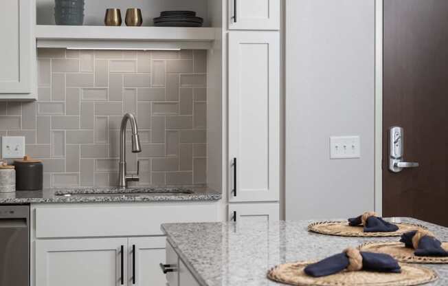 A kitchen with a marble countertop and white cabinets.