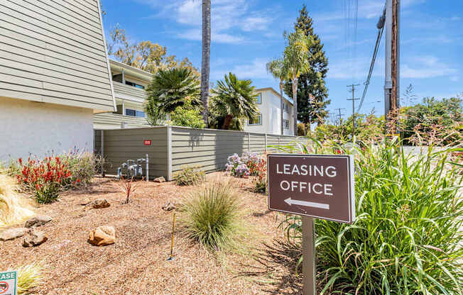 A brown sign that says Leasing Office stands in a yard.