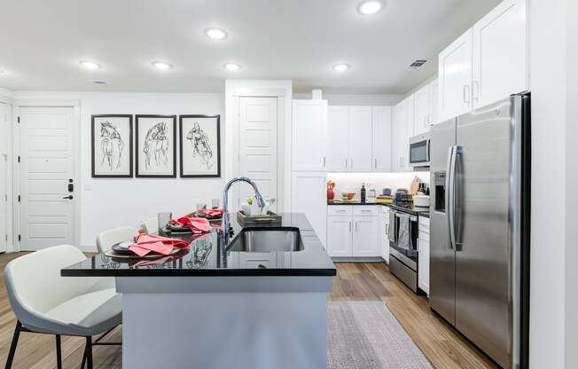a white kitchen with stainless steel appliances and a black counter top