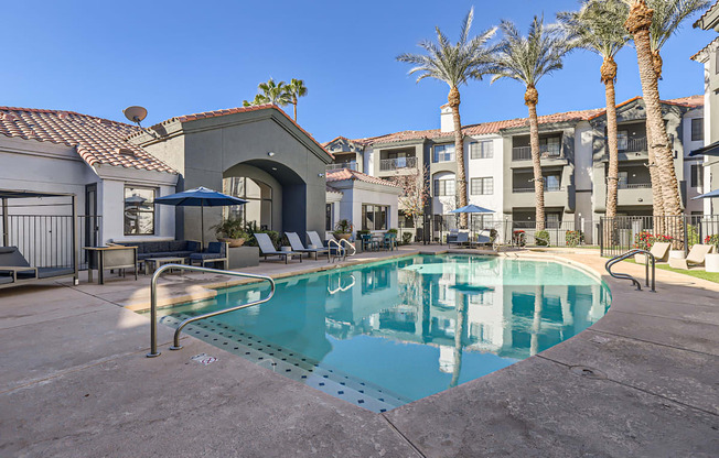 A pool in a courtyard surrounded by palm trees and buildings.
