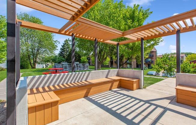 a patio with wooden benches and a pergola