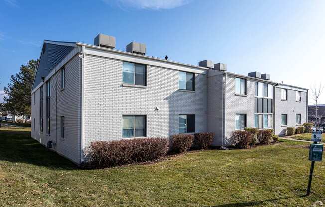 A white building with a black roof and a sign in front of it.