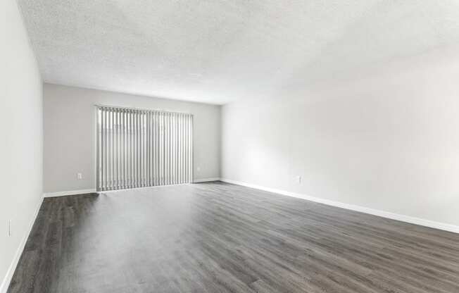 an empty living room with white walls and wood floors