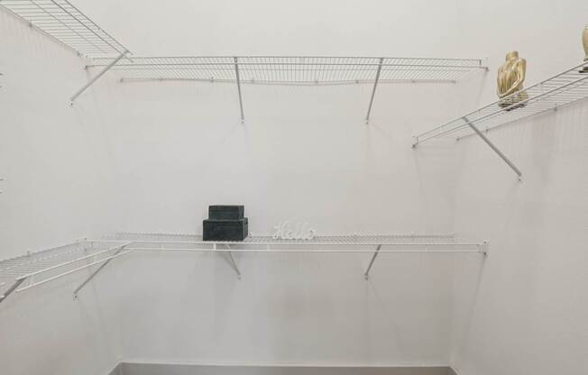 A white wall with a wire shelf and a black box on it.