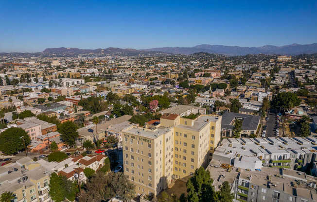 A cityscape with a large building in the center and a mountain range in the distance.