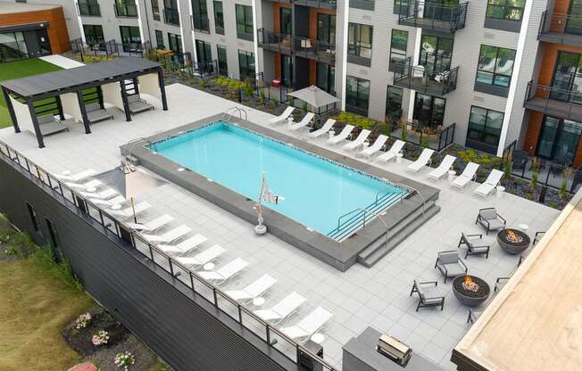 an aerial view of a swimming pool with lounge chairs and umbrellas in front of a