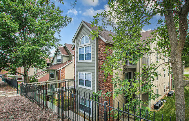 an apartment building with a fence and trees