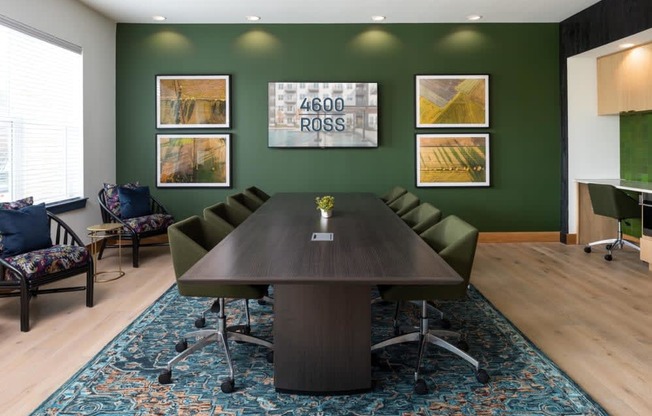a conference room with green walls and a large wooden table with a vase of flowers on