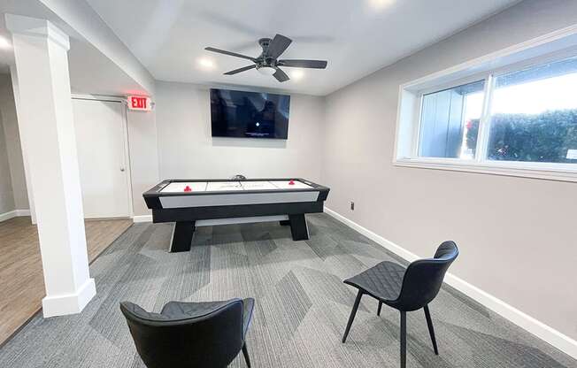 a game room with an air hockey table and a flat screen tv