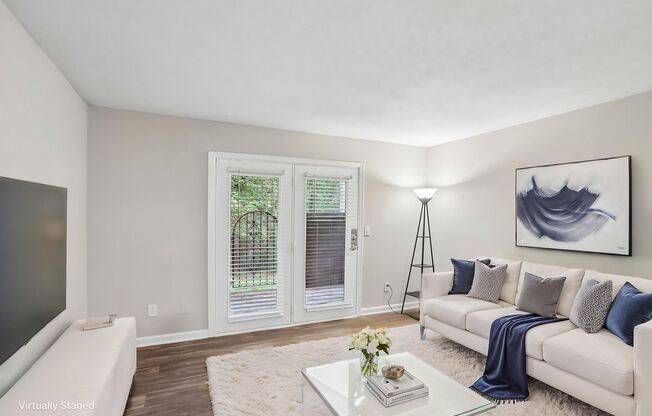 A living room with a white couch, a coffee table, and a painting on the wall.