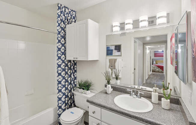 A bathroom with a white toilet, sink, and a mirror.