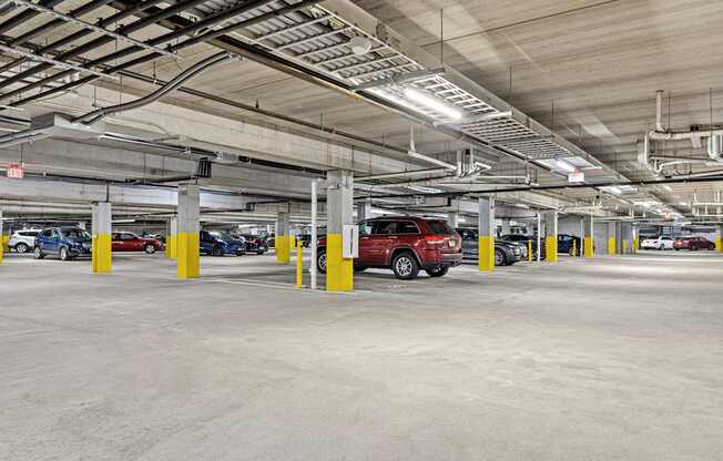 A parking garage with a red car parked in the middle.