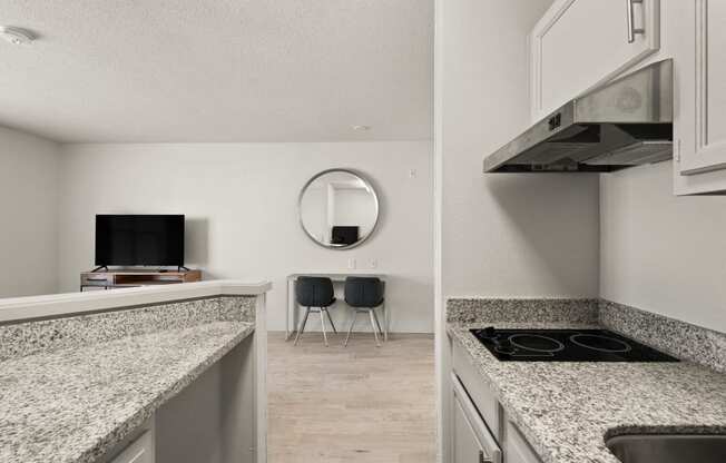 a kitchen with granite counter tops and a living room with a tv