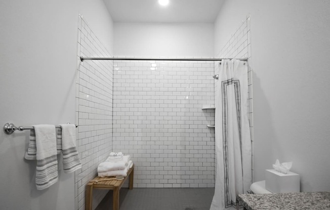 a white bathroom with a shower and a table with towels at 20 Midtown, Birmingham, Alabama