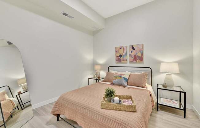 A bedroom with a bed, nightstand, and two wall lamps.