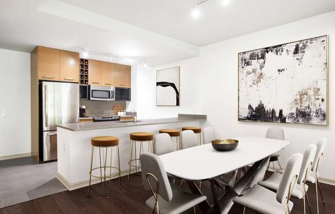 a dining area with a white table and chairs and a kitchen in the background