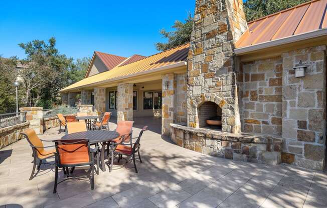 a backyard patio with a table and chairs and a stone fireplace at The Verandah, Texas, 78726