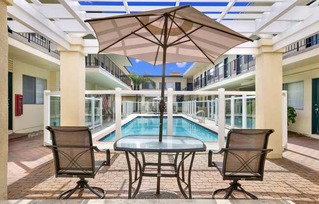 a patio with a pool and a table with chairs and an umbrella at Olive Tree Apartments, Torrance, CA 90503