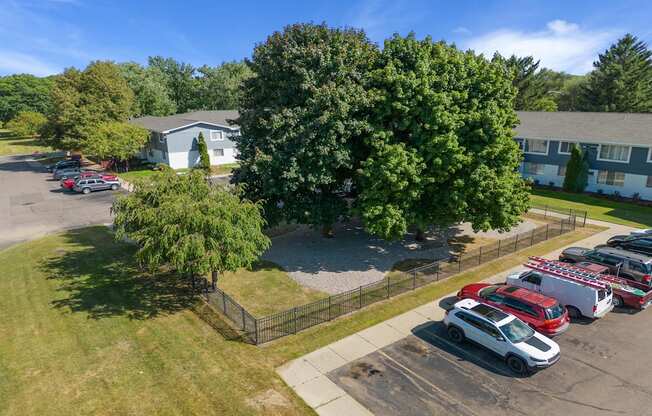 Aerial view of a parking lot with cars in front of a house at Town & Country Apartments - Wixom, MI, Michigan